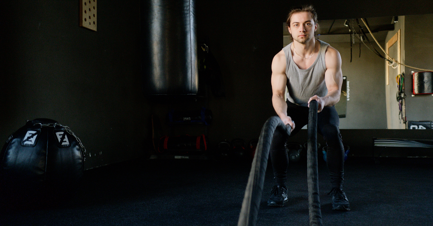 Man exercising in a gym with heavy battle ropes