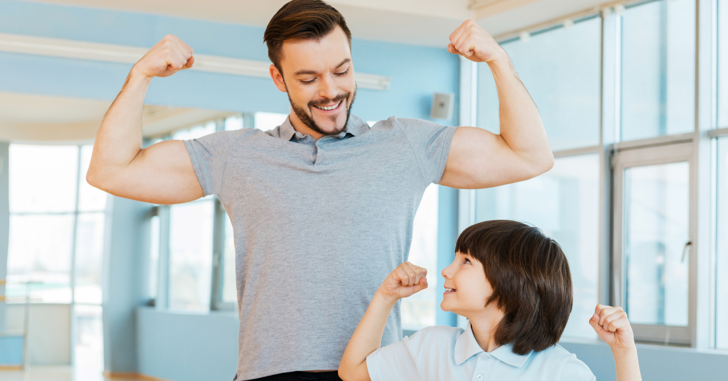 Smiling father flexing his biceps beside his son, who copies him