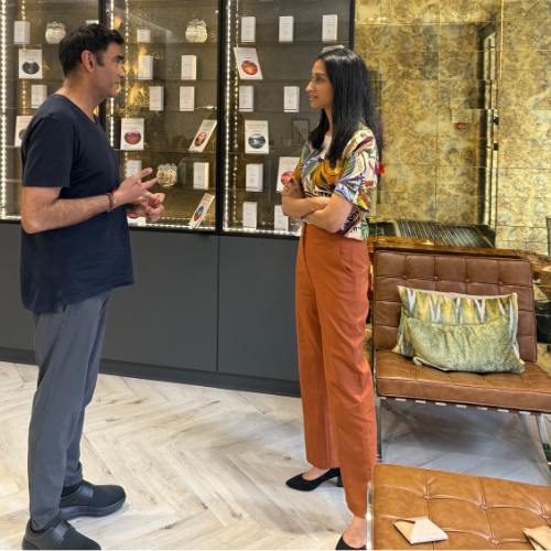 Dr Madhvi Patel talking with a male colleague in a clinic lounge with lit display cabinets