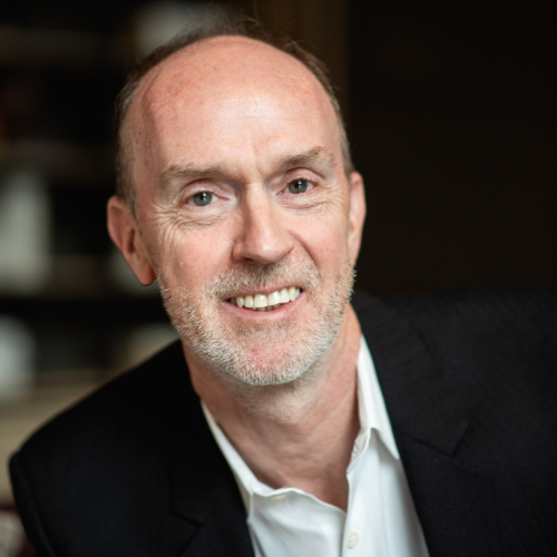 Dr Gareth Morris-Stiff smiling, wearing a dark jacket and an open-necked white shirt
