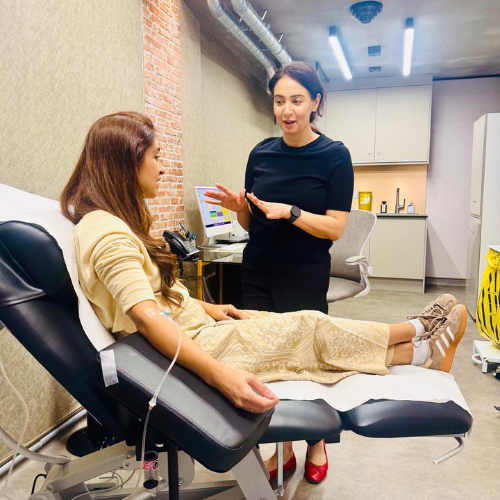Dr Kiran Dhillon talking with a patient who is receiving an intravenous drip in a reclining treatment chair