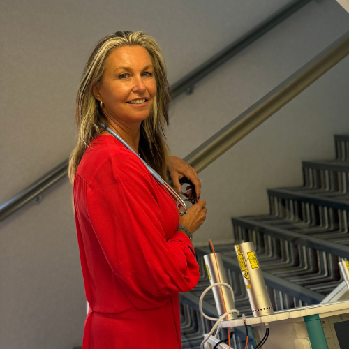 Dr Simone Kuter in a red dress beside medical equipment at the foot of a staircase