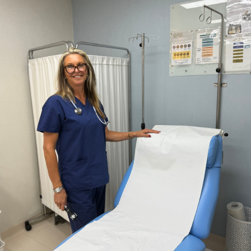 Dr Simone Kuter in navy scrubs with a stethoscope, pulling paper over a treatment couch