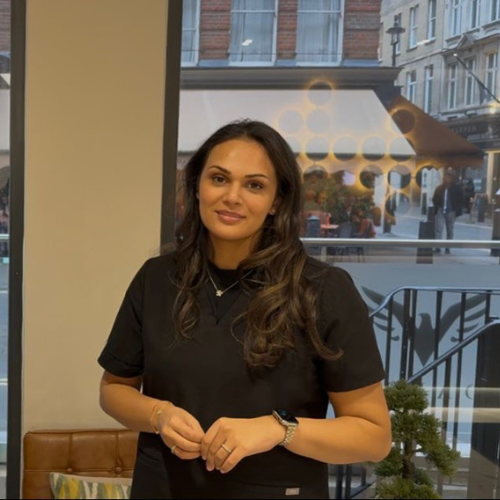 Nikita Desai standing in black scrubs in a clinic beside a window onto the street