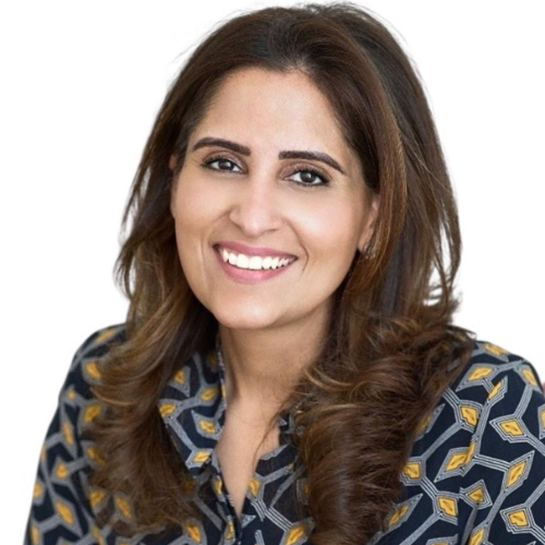 Rakhee Mediratta smiling, wearing a navy and gold patterned blouse