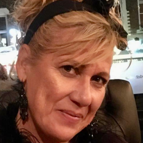 Close-up of Christina Walker with blonde hair, a black headband and drop earrings