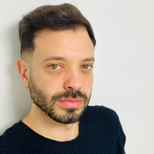 Dr Moe Irshidat, with short dark hair and a beard, wearing a navy jumper against a pale wall