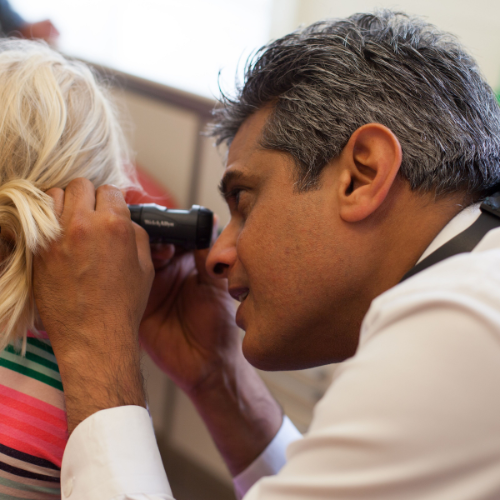 Hamid Daya examining a patient’s ear with an otoscope